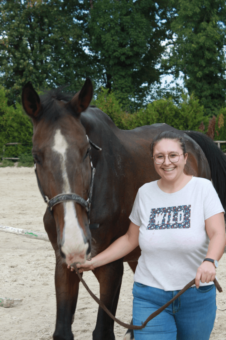 a woman standing next to a brown horse